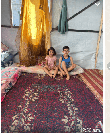 2 kids smiling in a makeshift tent