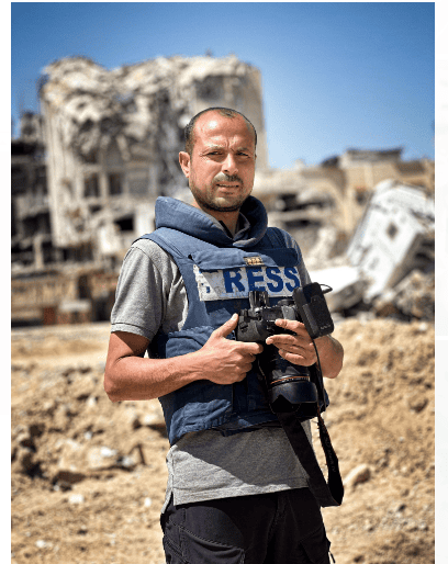 Man in press gear holding camera